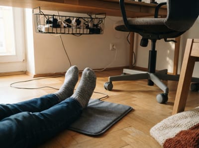 Infra lábmelegítő párna az íróasztal alatt, gyapjúzoknis láb pihen rajta